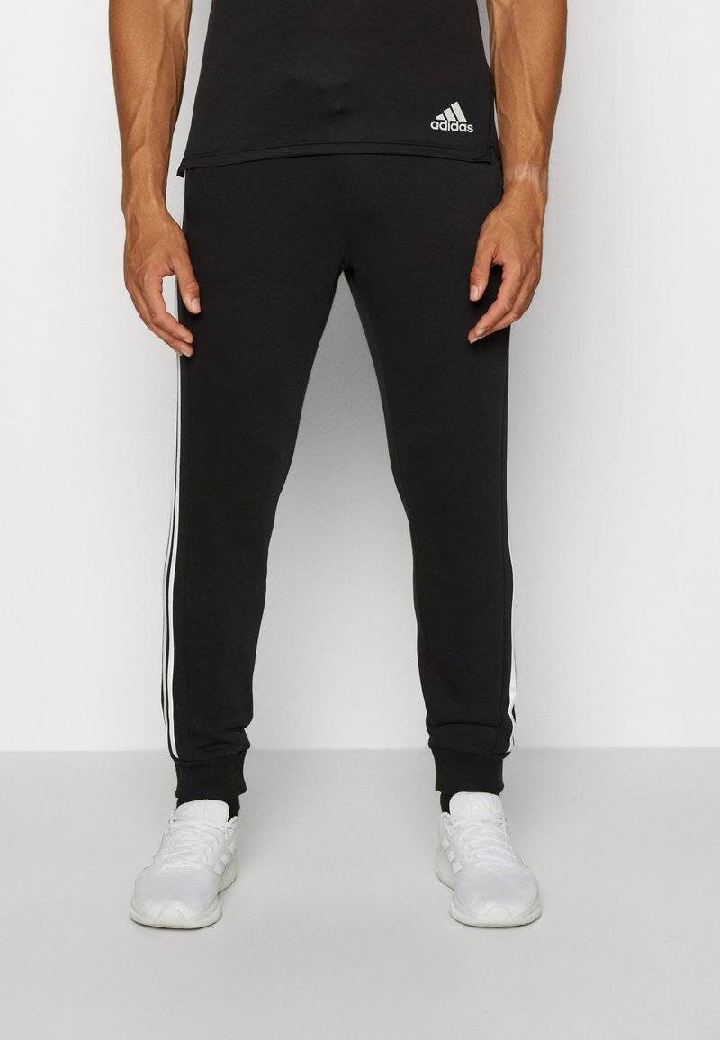 adidas Sportswear adidas Sportswear ESSENTIALS TAPERED CUFF 3 STRIPES PANTS - Tracksuit bottoms - black white 2025