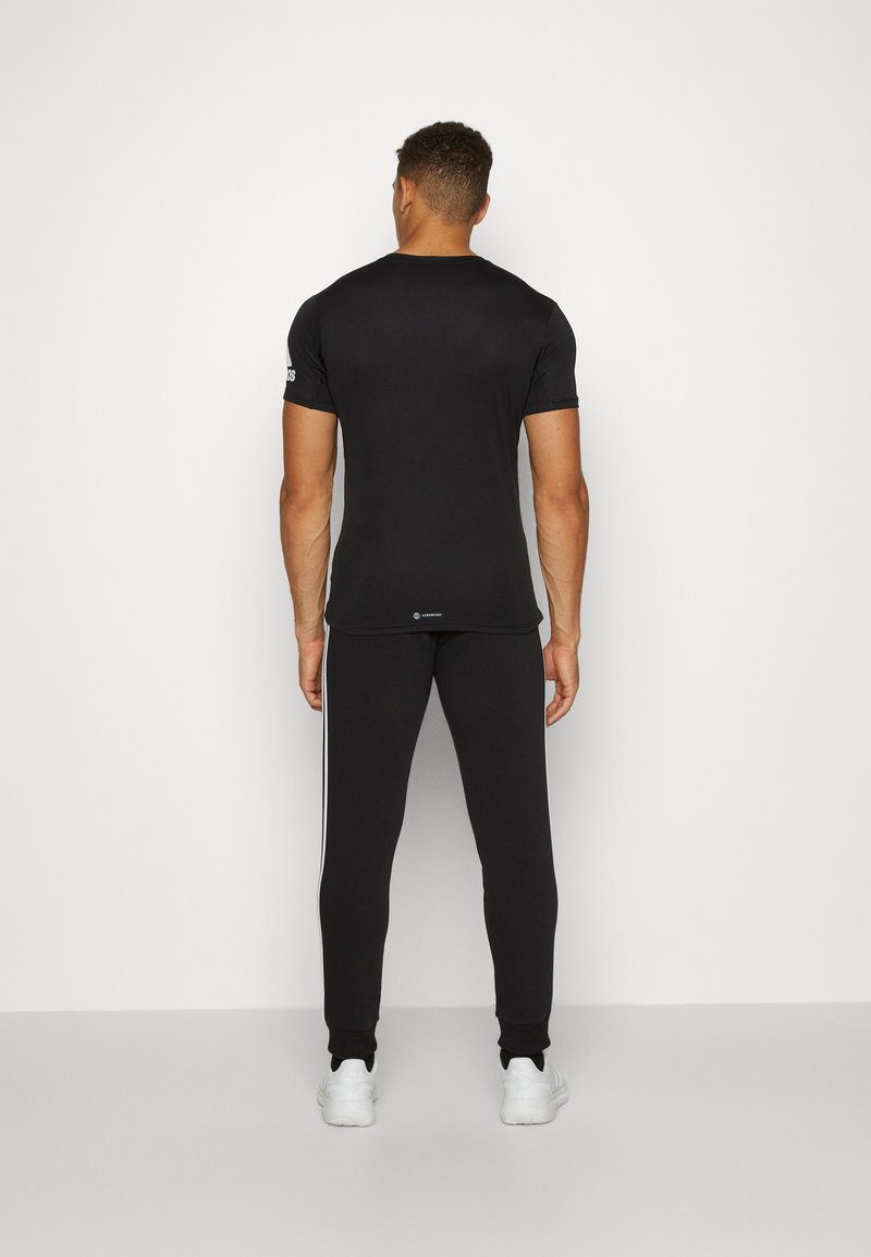 adidas Sportswear adidas Sportswear ESSENTIALS TAPERED CUFF 3 STRIPES PANTS - Tracksuit bottoms - black white 2025
