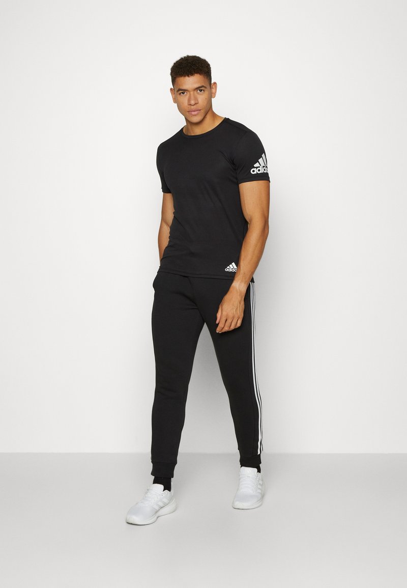 adidas Sportswear adidas Sportswear ESSENTIALS TAPERED CUFF 3 STRIPES PANTS - Tracksuit bottoms - black white 2025